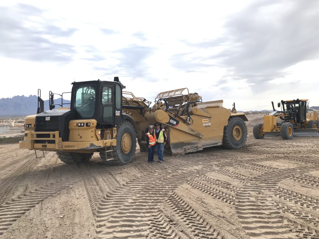 Construction couple in front of equipment